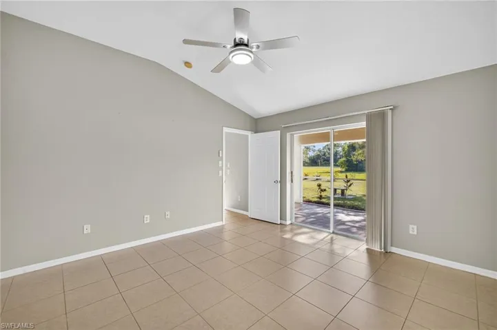 Empty room featuring vaulted ceiling, light tile patterned flooring, and ceiling fan