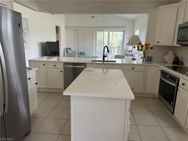 Kitchen featuring kitchen peninsula, appliances with stainless steel finishes, sink, and a kitchen island