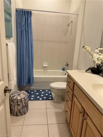 Full bathroom with toilet, vanity, tile patterned floors, and shower / bathtub combination with curtain