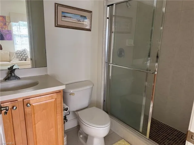 Bathroom with vanity, walk in shower, tile patterned floors, and toilet