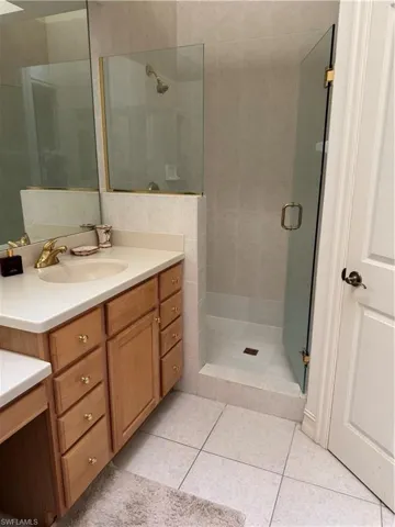 Bathroom featuring vanity, walk in shower, and tile patterned flooring