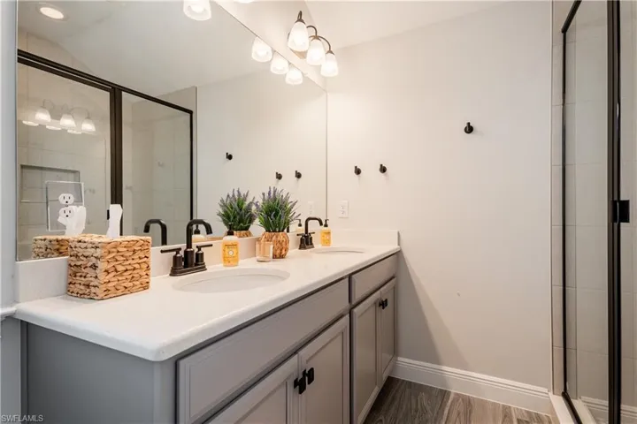 Full bathroom with a shower stall, double vanity, and vaulted ceiling