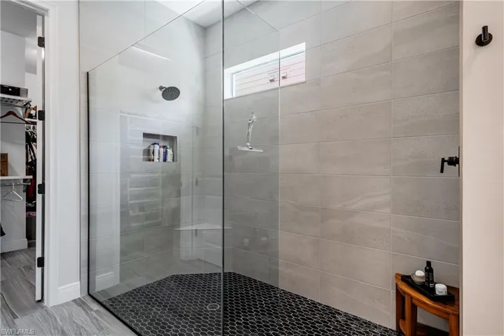 Bathroom with a shower stall, a walk in closet, and wood finished floors