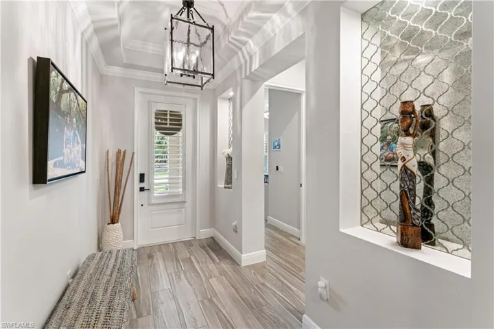 Entryway featuring light wood-style floors, a chandelier, and ornamental molding