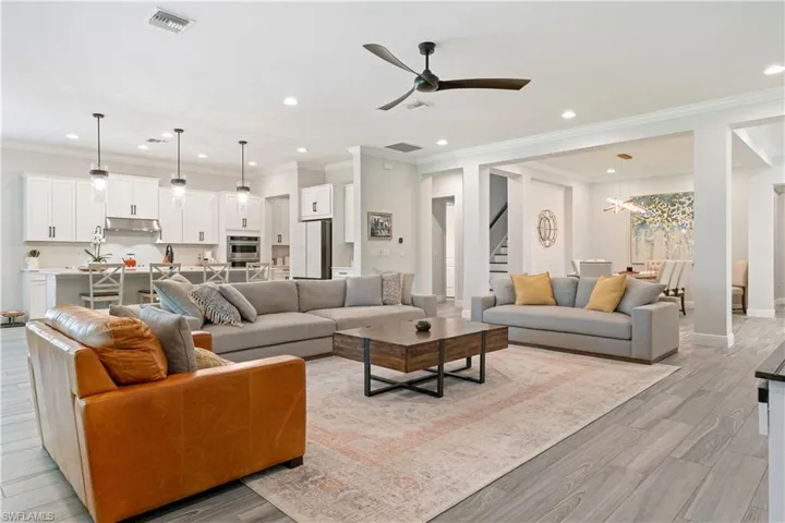 Living area with a ceiling fan, crown molding, light wood-type flooring, recessed lighting, and a chandelier