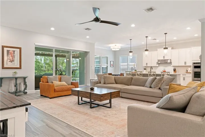 Living area with ceiling fan, light wood-style floors, healthy amount of natural light, crown molding, and recessed lighting