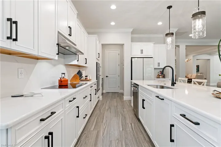 Kitchen featuring white cabinets, pendant lighting, crown molding, freestanding refrigerator, and light wood finished floors