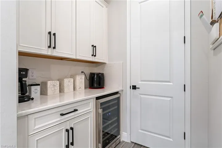 Bar featuring white cabinets and wine cooler