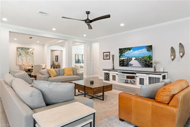Living room featuring ornamental molding, a ceiling fan, light wood-style floors, and recessed lighting