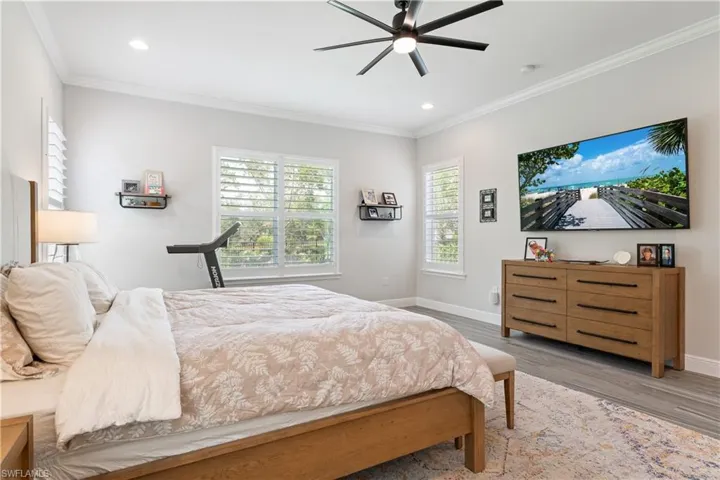 Bedroom with ornamental molding, a ceiling fan, multiple windows, wood finished floors, and recessed lighting