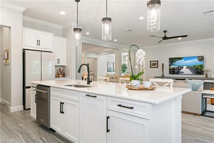 Kitchen featuring white cabinets, open floor plan, freestanding refrigerator, an island with sink, and light wood-type flooring
