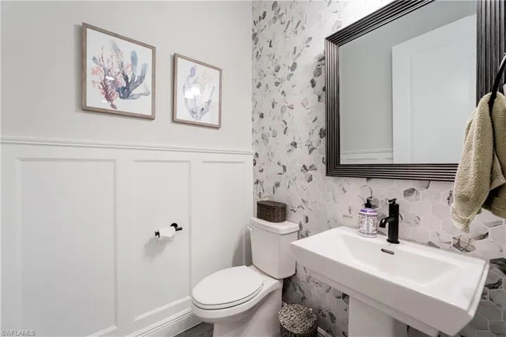 Half bath with a wainscoted wall and a decorative wall