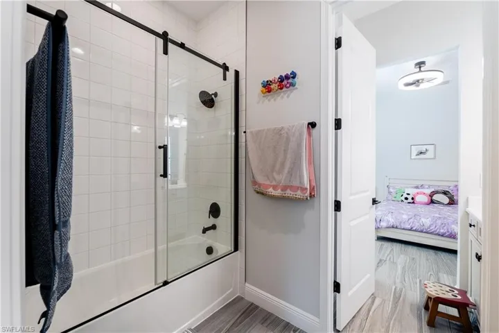 Full bathroom featuring shower / bath combination with glass door, ensuite bathroom, and light wood-style floors