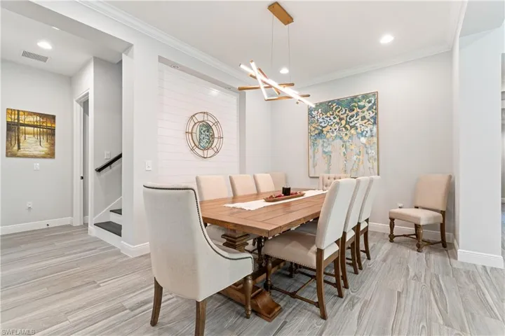 Dining room featuring recessed lighting, a chandelier, ornamental molding, light wood-style flooring, and stairs