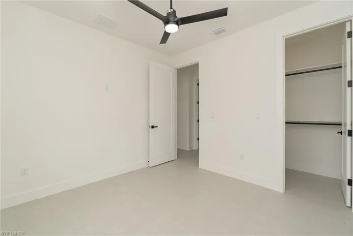 Unfurnished bedroom featuring light tile patterned flooring, a closet, and ceiling fan