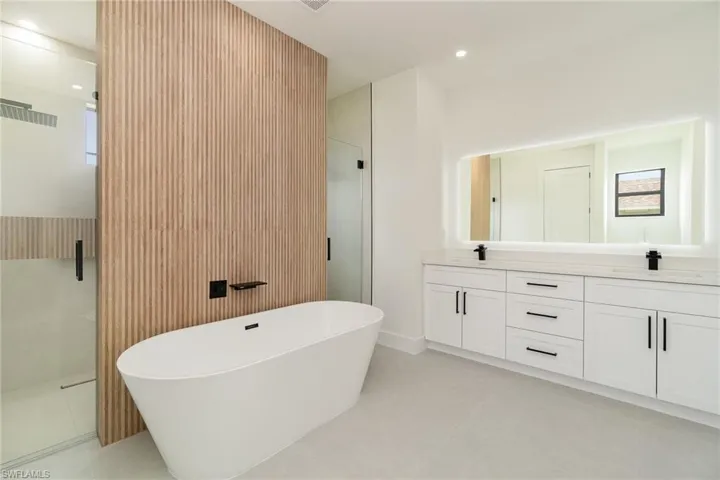 Bathroom featuring plus walk in shower, tile patterned floors, and double sink vanity
