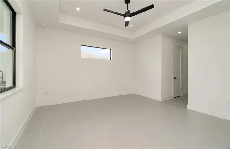 Empty room featuring light tile patterned flooring, a raised ceiling, and ceiling fan