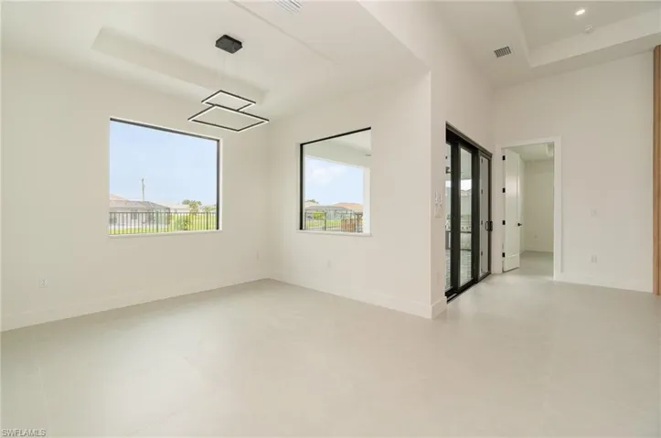 Unfurnished room featuring a healthy amount of sunlight, light tile patterned floors, and a tray ceiling