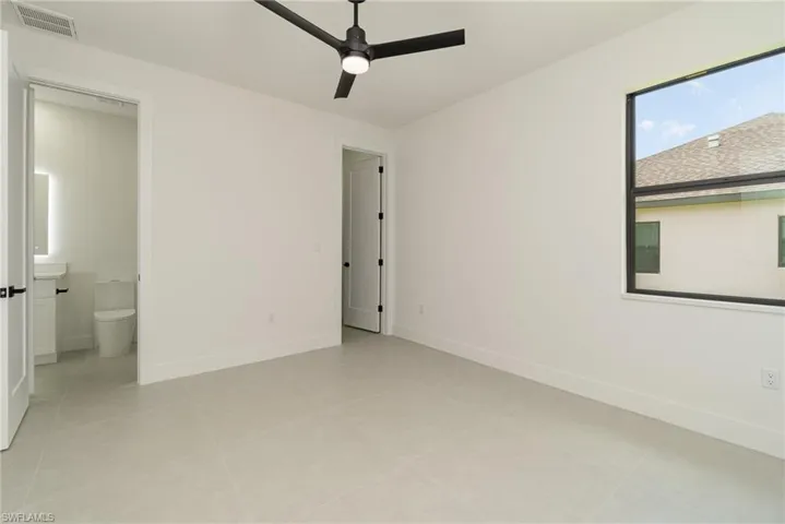 Unfurnished bedroom featuring ensuite bathroom, ceiling fan, and light tile patterned floors