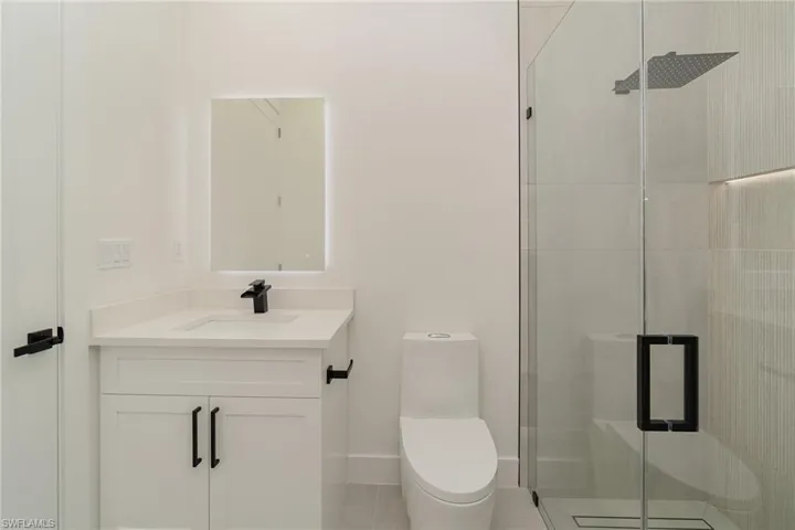 Bathroom with tile patterned flooring, a shower with door, toilet, and vanity