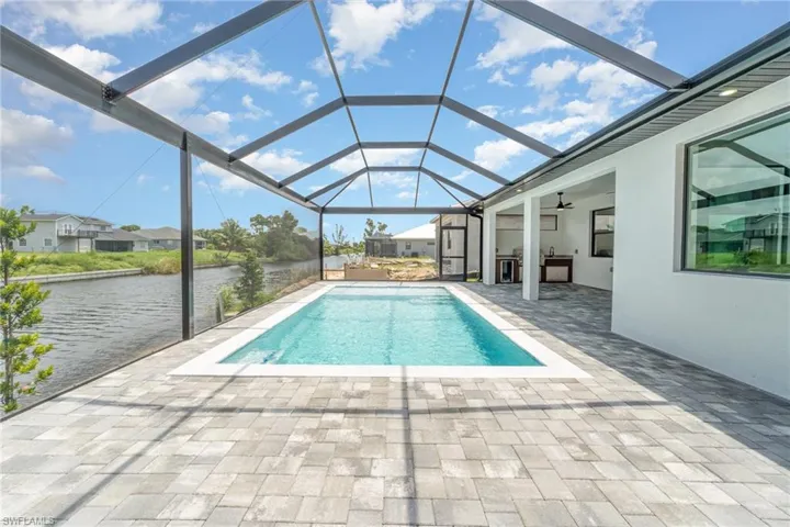 View of pool featuring glass enclosure, a patio, a water view, and ceiling fan- screen to be installed