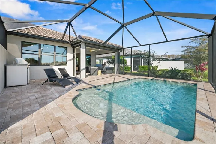 Outdoor pool featuring a sunroom, glass enclosure, a patio, and a grill