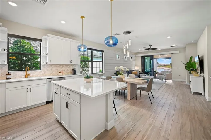 Kitchen with white cabinetry, open floor plan, wood tiled floors, pendant lighting, and a center island
