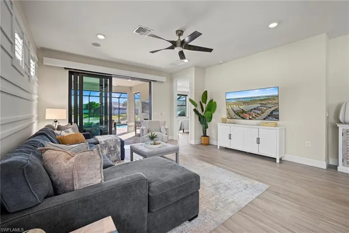 Living area with light wood-type flooring, a ceiling fan, and recessed lighting