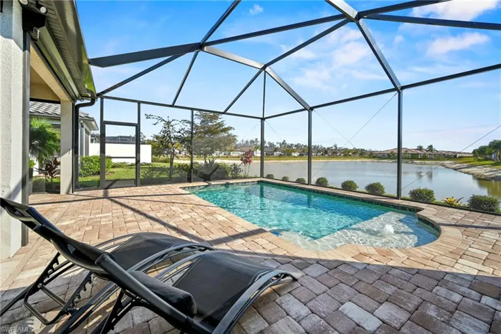 Swimming pool featuring a sunroom, a patio, glass enclosure, and a water view