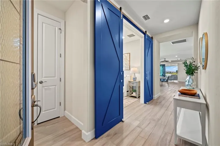 Corridor with a barn door, light wood-style flooring, and recessed lighting