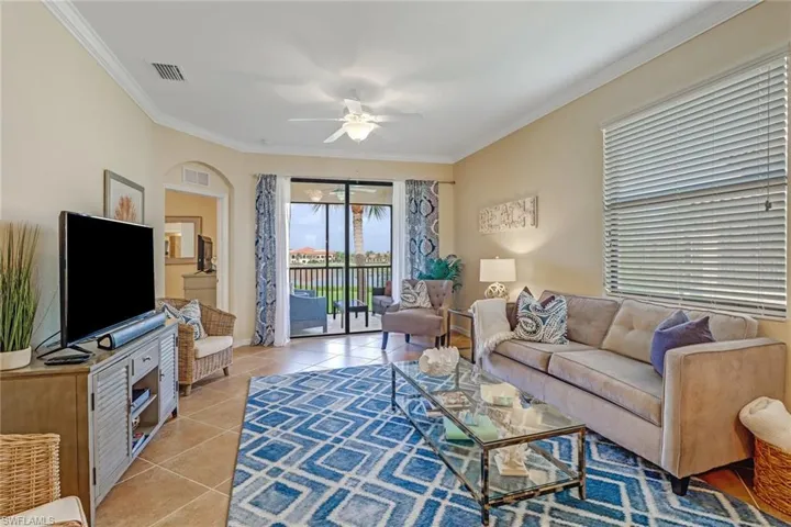 Living room featuring light tile patterned flooring, a ceiling fan, ornamental molding, and arched walkways