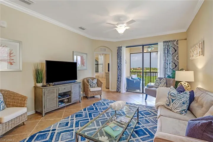 Tiled living room featuring ornamental molding, ceiling fan, and arched walkways