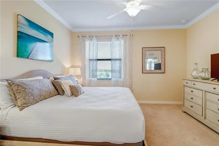 Bedroom featuring light carpet, ornamental molding, and ceiling fan