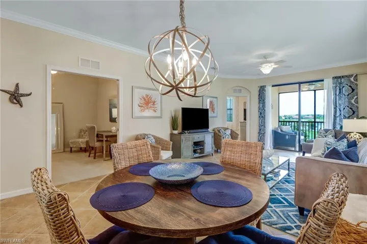 Dining space featuring ornamental molding, a chandelier, a ceiling fan, and light tile patterned flooring