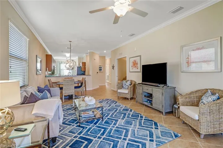 Living area with tile patterned floors, crown molding, and a ceiling fan