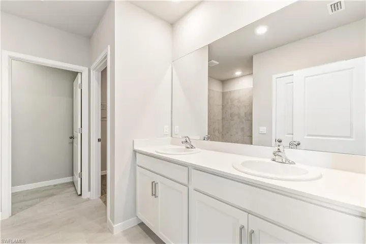 Bathroom featuring a walk in closet, recessed lighting, a tile shower, and light wood finished floors