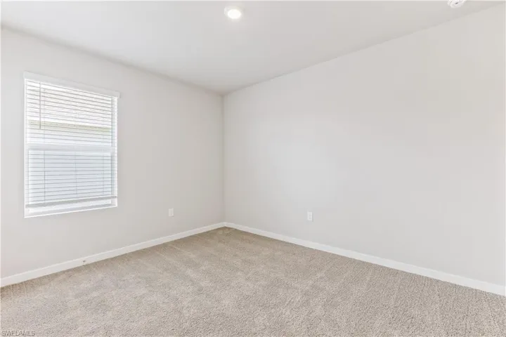 Carpeted spare room with baseboards and recessed lighting