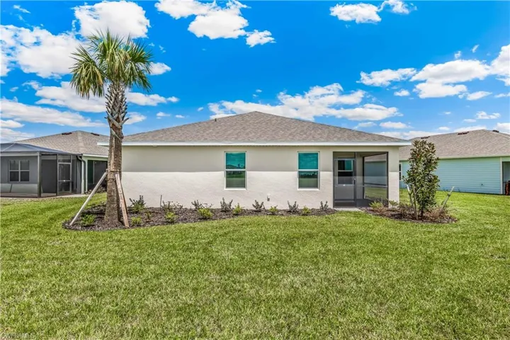 Rear view of property featuring a sunroom, a yard, stucco siding, and roof with shingles