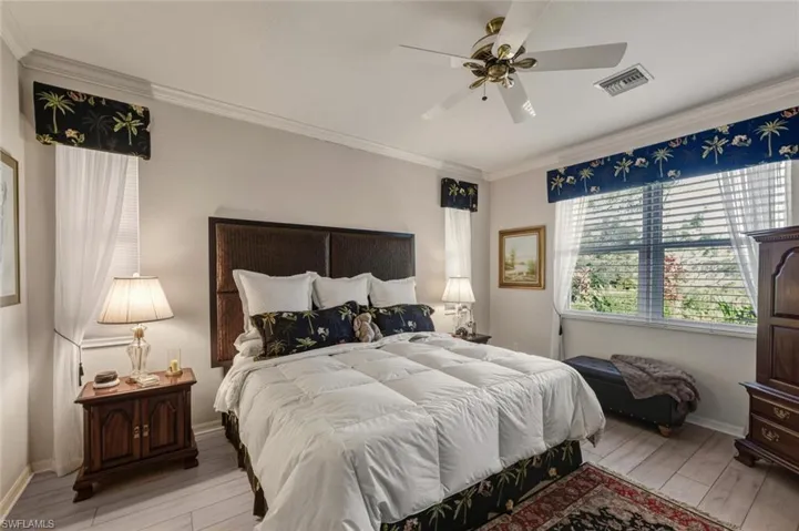 Bedroom with hardwood / wood-style flooring, crown molding, and a ceiling fan