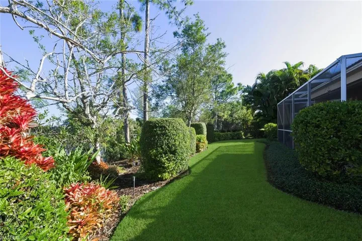 View of green lawn featuring glass enclosure and a sunroom