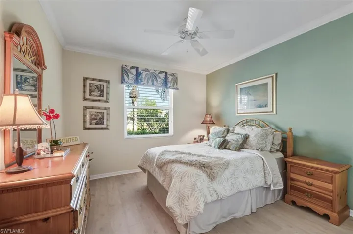 Bedroom featuring light wood-style floors, crown molding, and ceiling fan