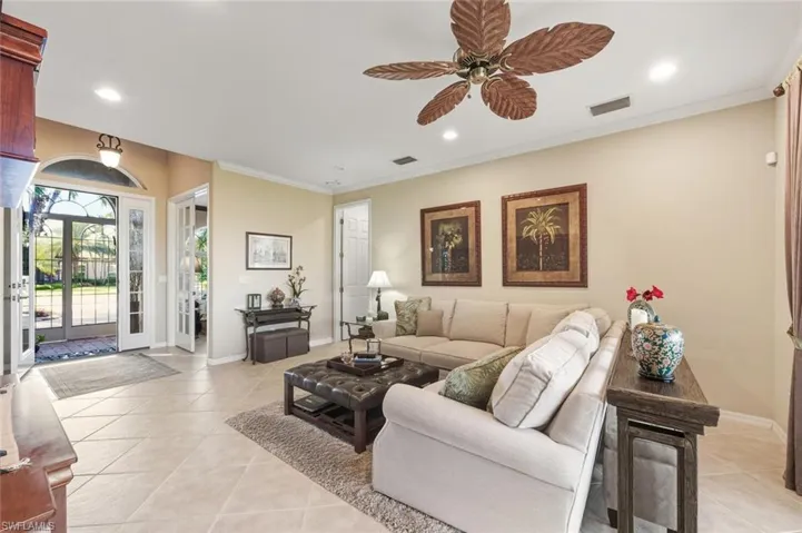 Living room with light tile patterned flooring, recessed lighting, crown molding, and ceiling fan