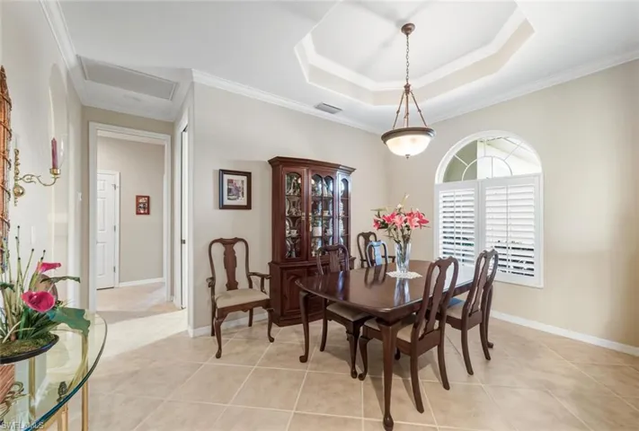 Dining space with a raised ceiling, ornamental molding, and light tile patterned floors