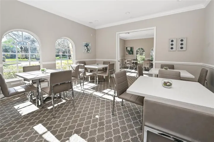 Dining area with crown molding, dark colored carpet, and plenty of natural light