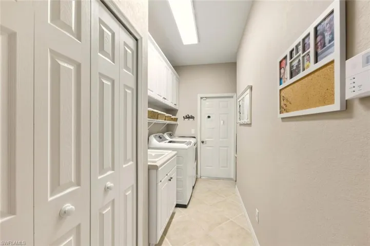 Laundry room featuring independent washer and dryer, light tile patterned floors, and cabinet space