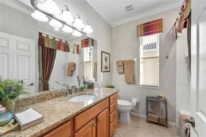 Full bath featuring vanity, crown molding, shower / bath combo, and light tile patterned floors