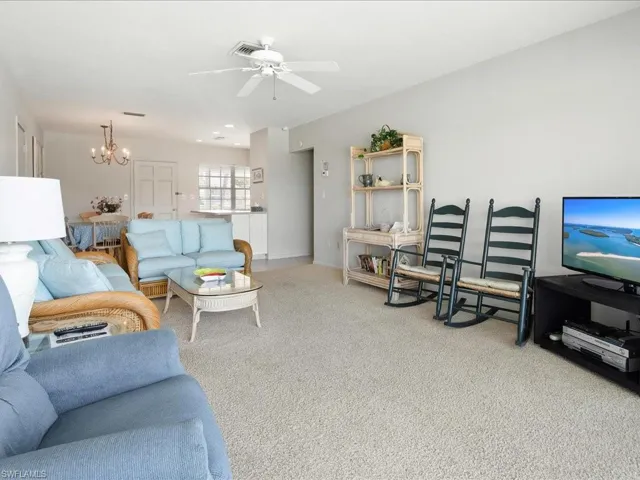 Living area featuring carpet flooring and ceiling fan with notable chandelier