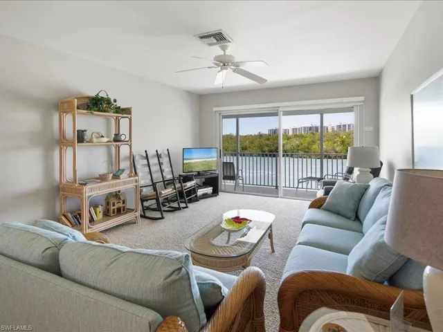 Living room with carpet, visible vents, and ceiling fan