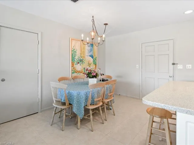 Dining space featuring light tile patterned floors, a notable chandelier, and baseboards