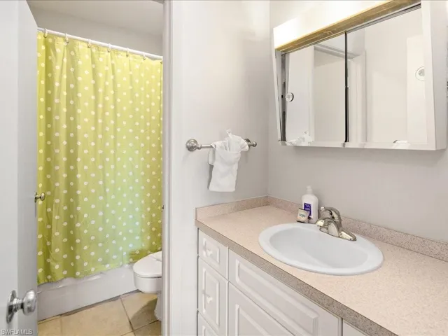 Full bath with tile patterned flooring, vanity, toilet, and a shower with curtain